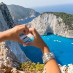 Tourist taking a photo of Navagio Beach from the Zakynthos viewpoint