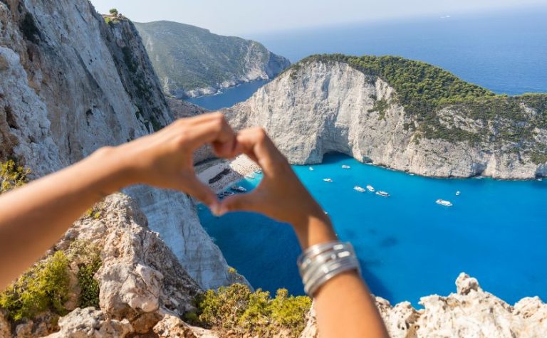 Tourist taking a photo of Navagio Beach from the Zakynthos viewpoint