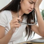Woman holding an eye drop bottle, treating eye irritation from salt water exposure in Zakynthos